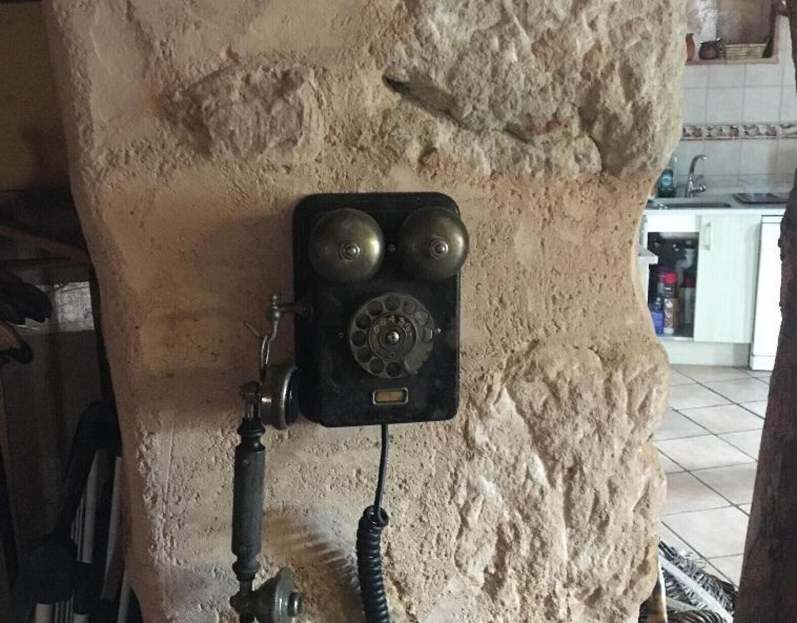 Un teléfono antiguo de disco montado en una pared con textura.