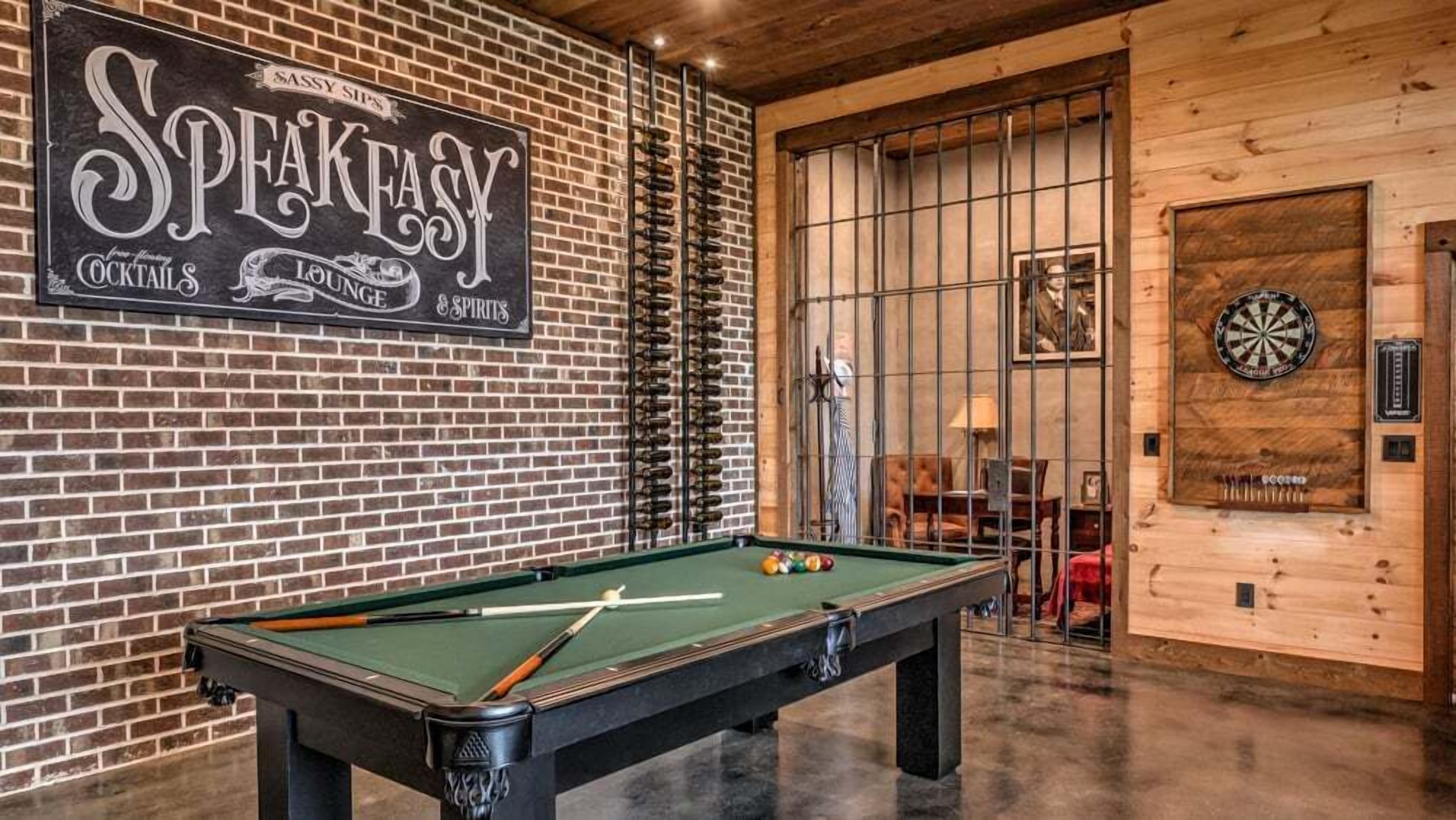 Une table de billard dans une pièce avec un mur en briques et une enseigne indiquant « Speakeasy Cocktails Lounge & Spirits ».