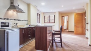 Una cocina equipada con microondas, tostadora y refrigerador, armarios de madera, una isla grande y un ventanal.
