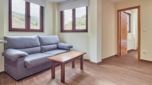Una sala de estar con un sofá, una mesa de centro de madera y dos ventanas con persianas.