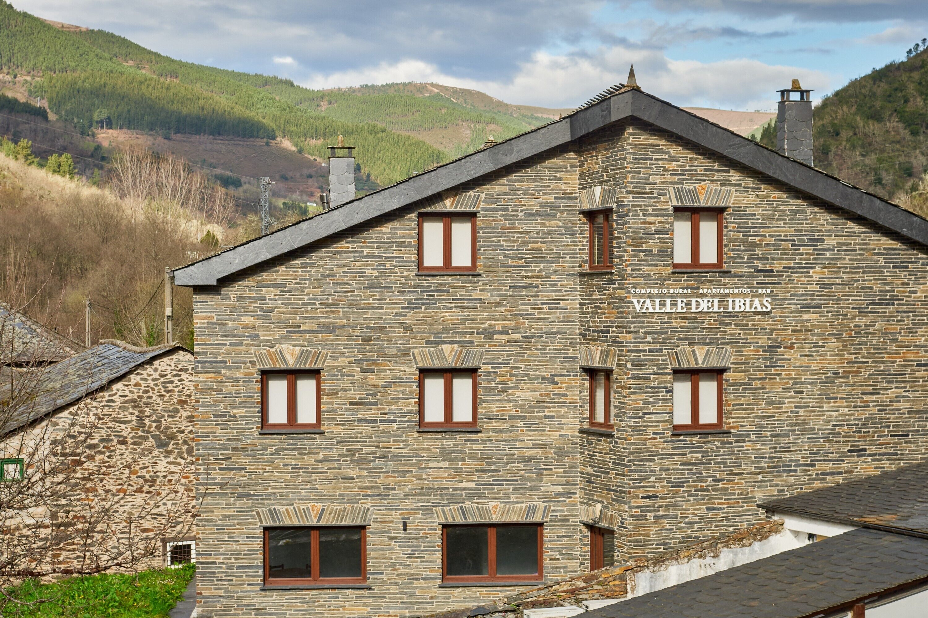 Un edificio de piedra con varias ventanas y un cartel que dice 'Valle del Ibias'.