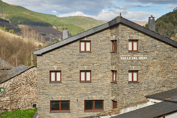 Un bâtiment en pierre doté de nombreuses fenêtres et d’une enseigne sur laquelle on peut lire « Valle del Ibias ».