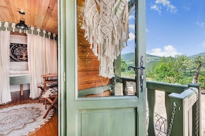 Uma cabana de madeira com vista para o campo, um enfeite de macramé e um tapete estampado.