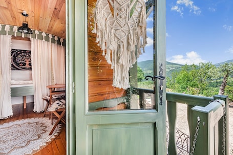 A wooden cabin with a view of the countryside, a macrame hanging, and a patterned rug.. Spacious, Bright and Welcoming Gîte with Mountain View, Private Terrace and Air Conditioning