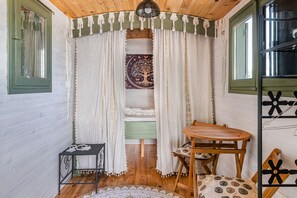 A cozy room with a bed, a small table, a chair, and a window with curtains. - Spacious, Bright and Welcoming Gîte with Mountain View, Private Terrace and Air Conditioning (Beaujeu)