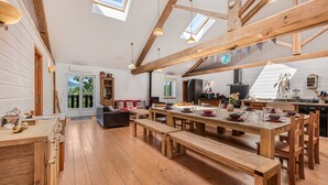 A spacious kitchen with wooden beams, a large dining table, and a view through the skylight. - Spacious, Bright and Welcoming Gîte with Mountain View, Private Terrace and Air Conditioning (Beaujeu)