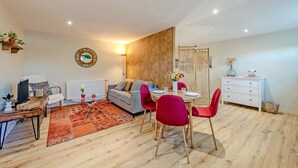 A modern living room with a sofa, dining table, chairs, and a coffee table. - Studio Apartment 'Le Grand Large' with Shared Terrace, Shared Garden and Wi-Fi (Lopérec)