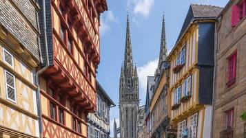 Une rue bordée de bâtiments traditionnels à colombages, avec une cathédrale gothique en arrière-plan.