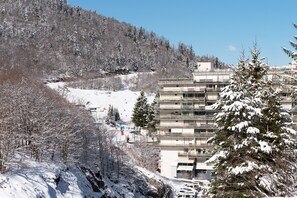 A multi-story building with a modern architectural design, surrounded by snow-covered trees and a mountainous backdrop.