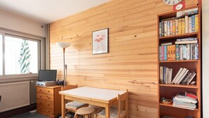 Una habitación con pared de madera, una estantería, un escritorio con silla y un radiador.