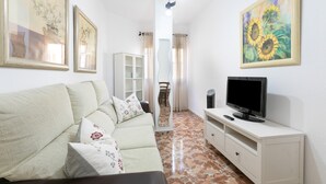 Una sala de estar con sofá, televisión, aparador y obras de arte enmarcadas en las paredes.
