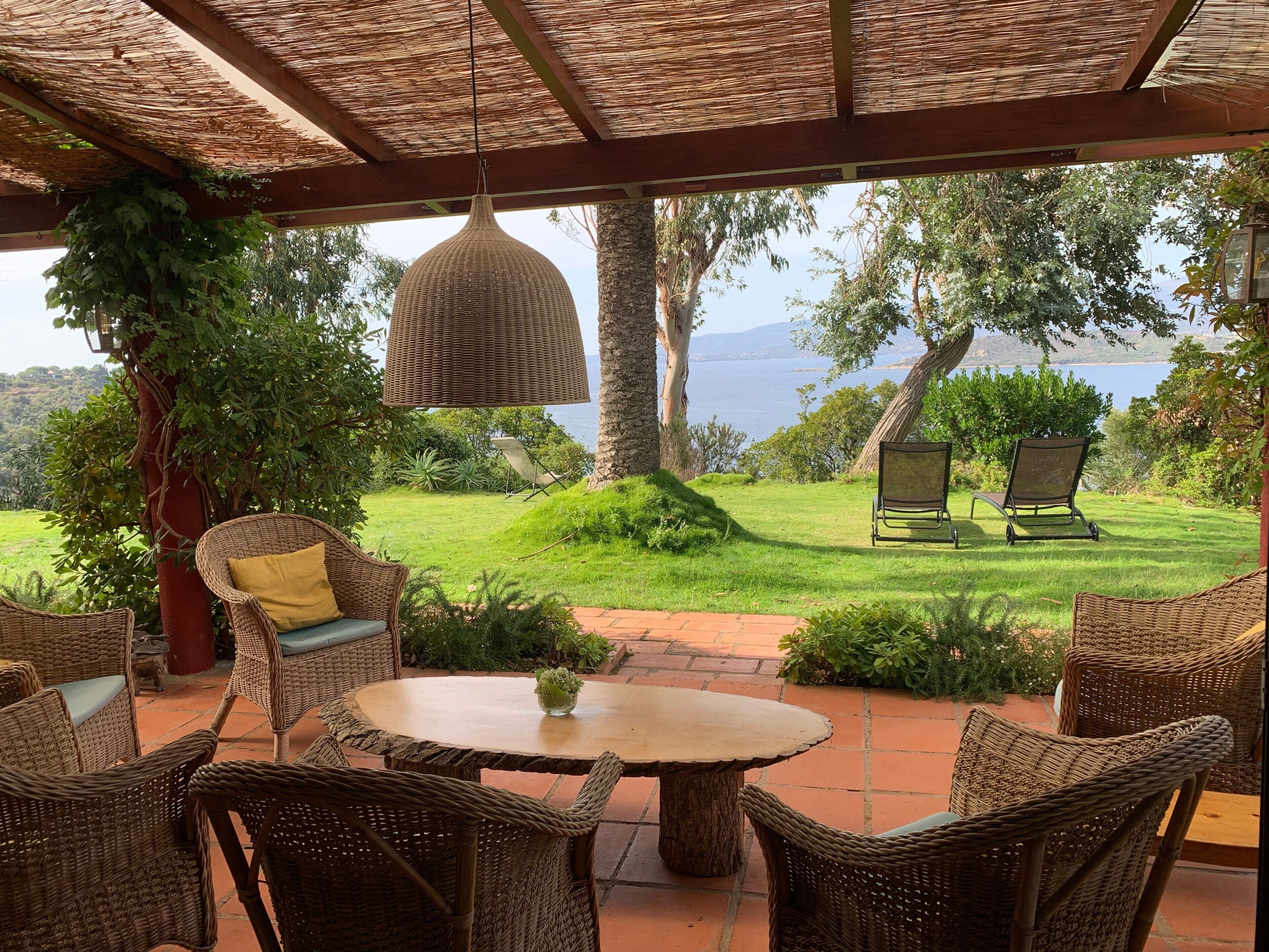 An outdoor seating area with wicker furniture, a round table, and a hanging lamp.