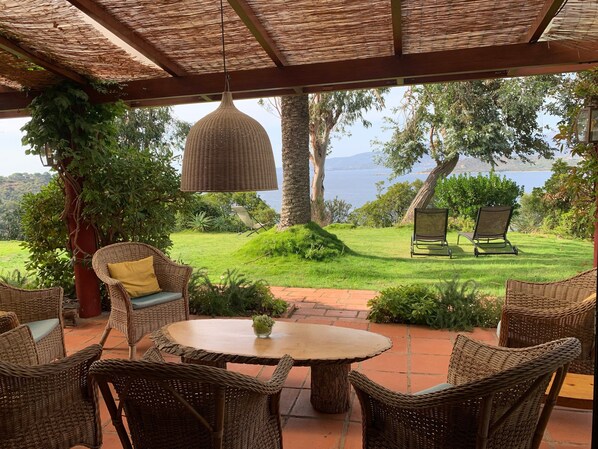 An outdoor seating area with wicker furniture, a round table, and a hanging lamp.