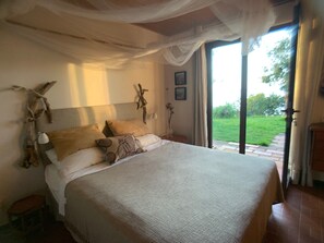 Een slaapkamer met een bed, nachtkastje, lamp en uitzicht op het landschap.