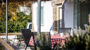 An outdoor seating area with a table and chairs, a covered patio, and a building with stone walls and blue shutters. - Country House 'Carrion' with Sea View, Wi-Fi and Air Conditioning (Periana)