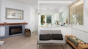 A modern living room with a fireplace, a sofa with cushions, a wicker bench, and a large mirror. - Country House 'Carrion' with Sea View, Wi-Fi and Air Conditioning (Periana)