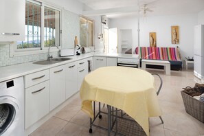 Eine moderne Küche mit Essbereich, einer Waschmaschine und einem Deckenventilator.