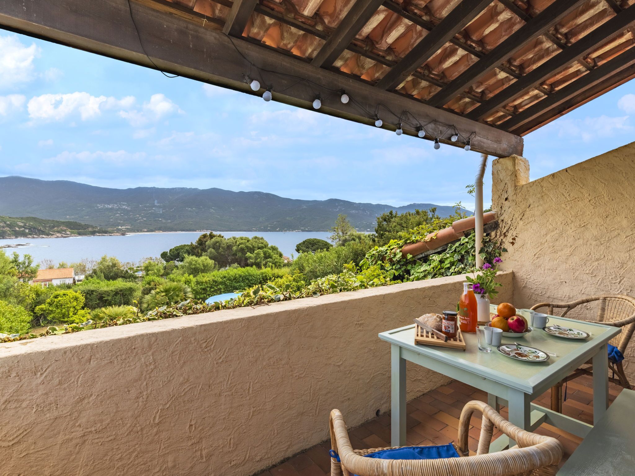 Un balcón con una mesa para dos, con vista a un lago y montañas.