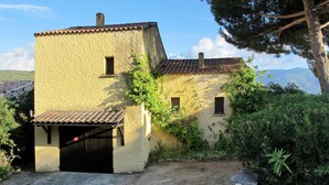 Un bâtiment de style rustique, doté d’un toit en tuiles, d’un petit porche et d’une allée gravillonnée.