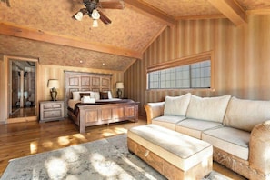 A spacious bedroom with a large bed, a sofa, a chest of drawers, and a large window. - Water's edge, enjoy this lakefront property. (Big Bear Lake)