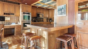A kitchen with wooden cabinets, a central island with stools, and a ceiling with recessed lighting. - Water's edge, enjoy this lakefront property. (Big Bear Lake)