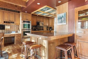 A kitchen with wooden cabinets, a central island with stools, and a ceiling with recessed lighting. - Water's edge, enjoy this lakefront property. (Big Bear Lake)