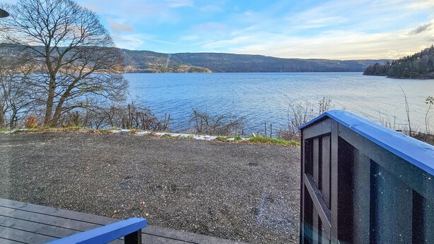 Une vue sur le lac depuis une terrasse, avec un chemin de gravier menant à l’eau.