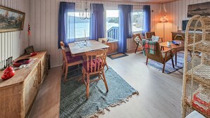 Une pièce chaleureuse avec une table à manger en bois, des chaises, un petit tapis et une vue sur l’eau.