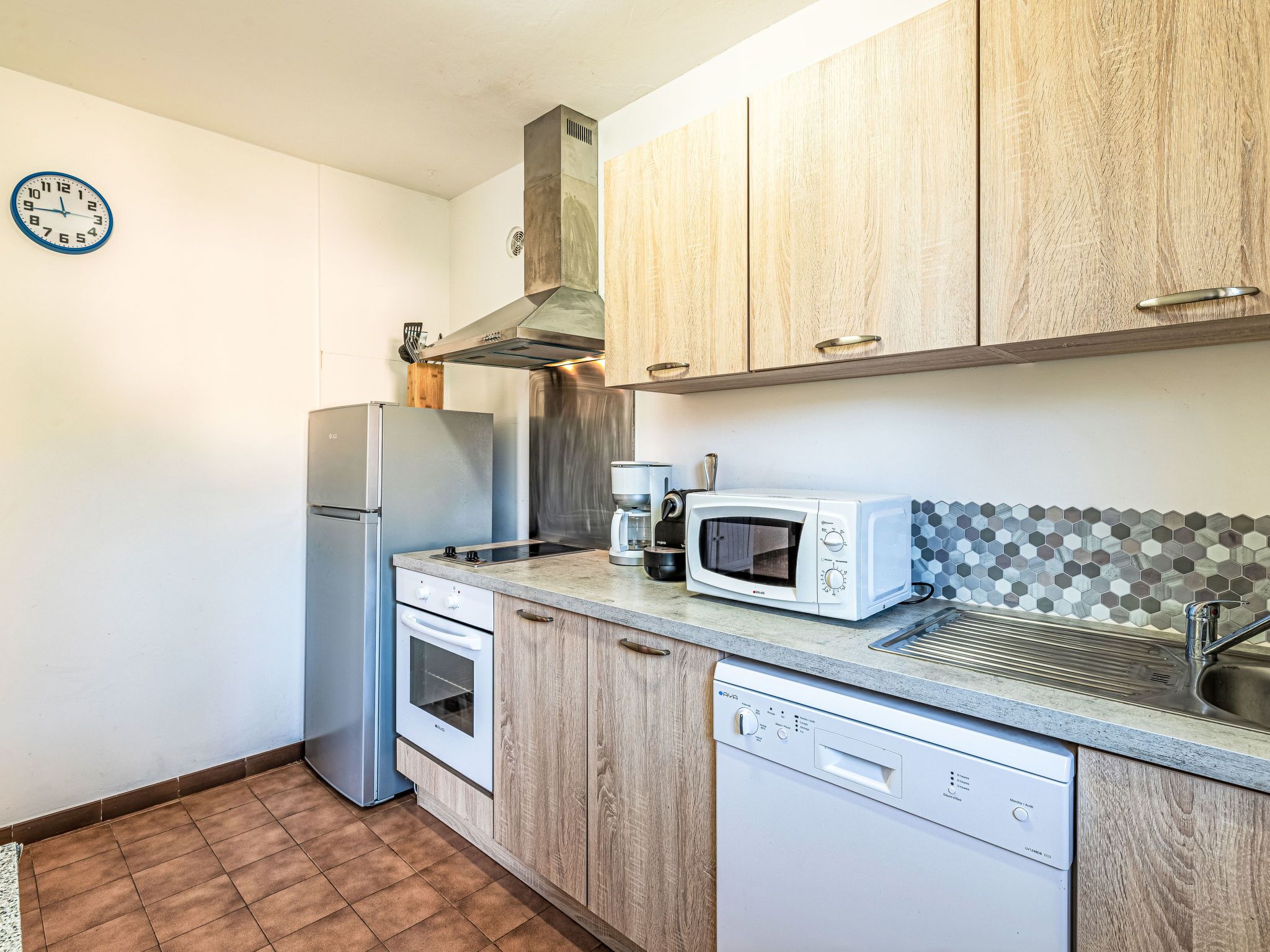 A compact kitchen with a refrigerator, microwave, oven, and dishwasher.