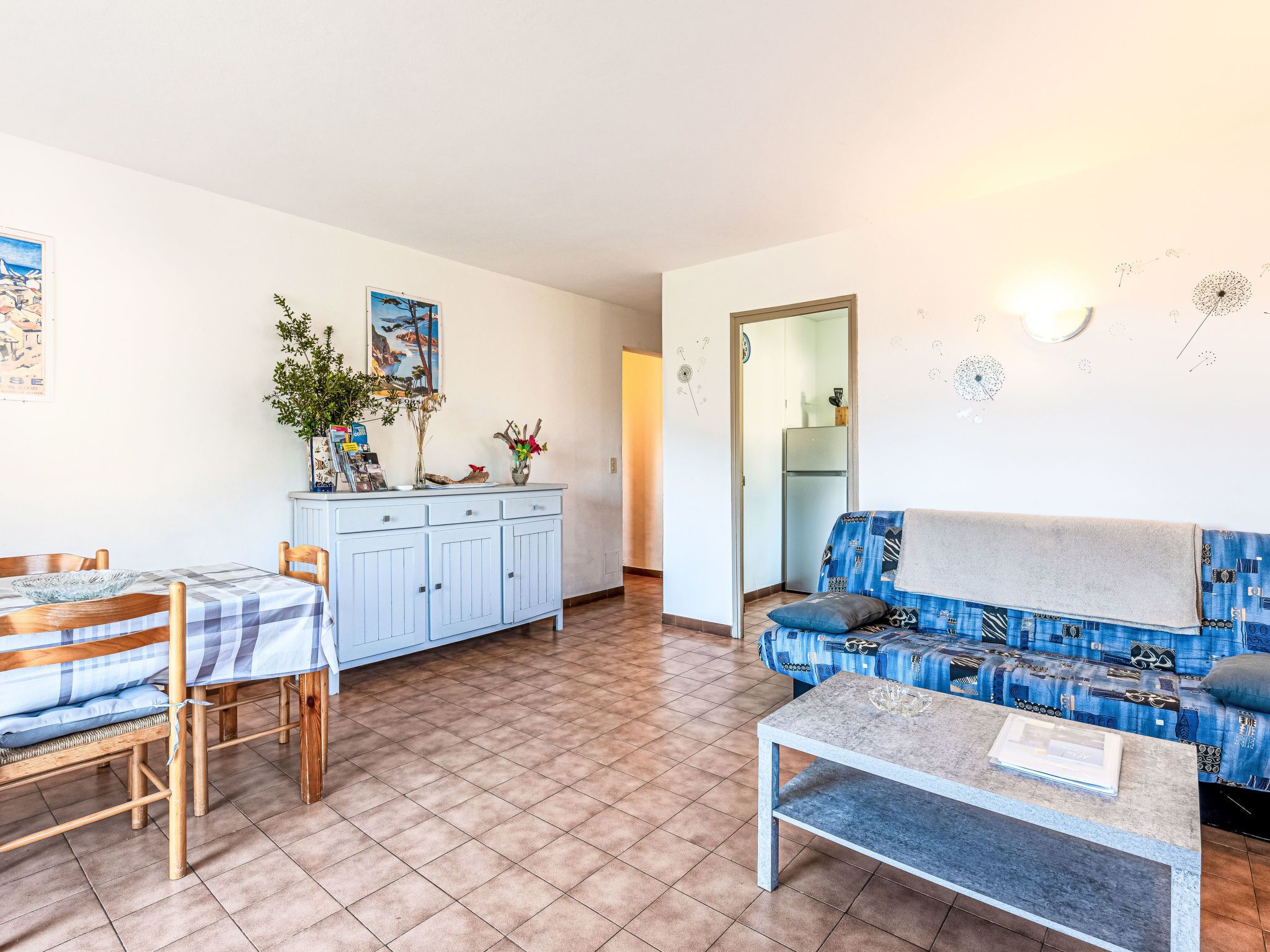 Een woonkamer met een bank, een salontafel, een eettafel met stoelen en een keuken met kasten.
