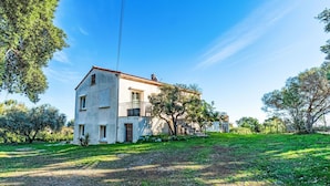 A two-story house with a balcony, surrounded by a grassy area and trees. - T2 Gabriello by Interhome (Solenzara)