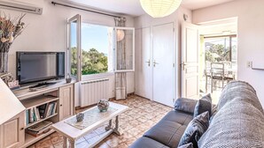 Un salon avec une télévision, un canapé, une table basse et une grande fenêtre.