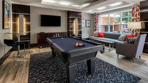 Una sala de estar moderna con una mesa de billar, un sofá y un televisor.