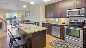 Una cocina moderna con armarios de madera oscura, electrodomésticos de acero inoxidable y una isla central con asientos.