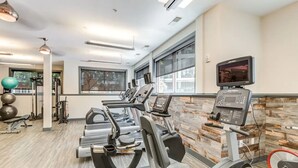 Un gimnasio con cintas de correr, pelotas de ejercicio y una pantalla de televisión.