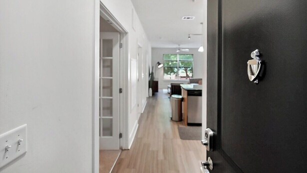 Una cocina moderna con una puerta negra, un ventanal visible y suelo de madera.