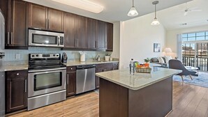 Een moderne keuken met donkerhouten kastjes, roestvrijstalen apparatuur en een centraal eiland.