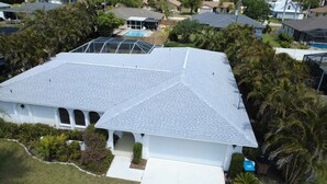 Una casa residencial con techo inclinado, un porche cubierto y una piscina.