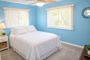 A bedroom with a bed, nightstand, lamp, and a ceiling fan.