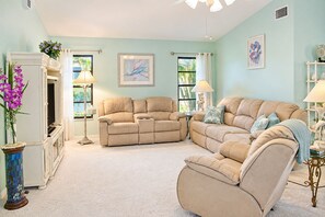 Una sala de estar con un sofá seccional color beige, una mesita redonda y una lámpara decorativa.