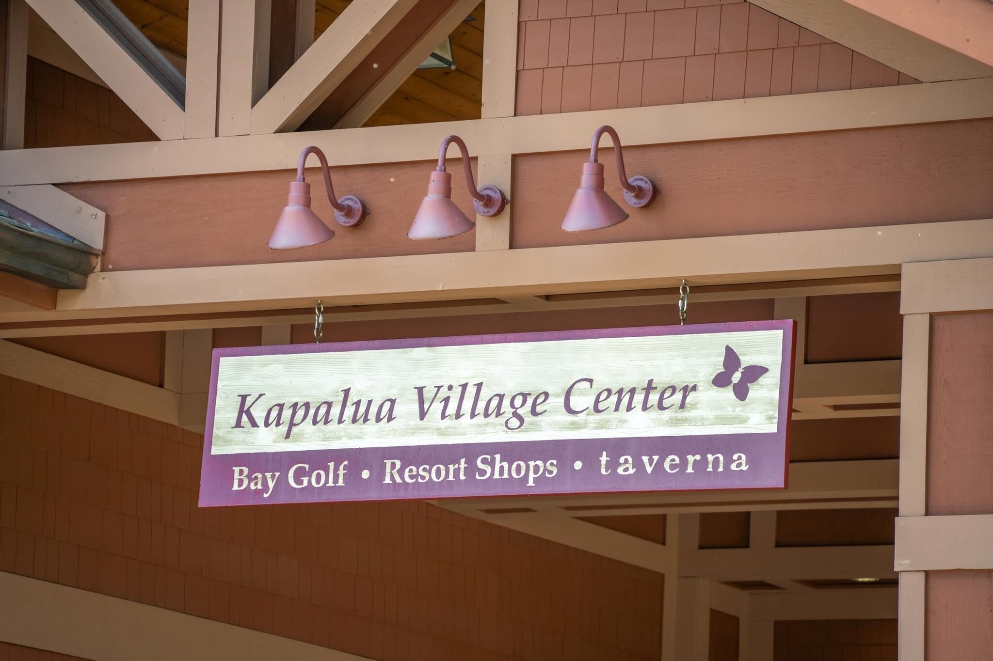 Un panneau indiquant l’entrée du centre du village de Kapalua, et précisant qu’on y trouve un terrain de golf, des boutiques de villégiature et un bar.