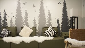 A room with a green sofa, white fluffy throw, and a chair with a white furry seat.