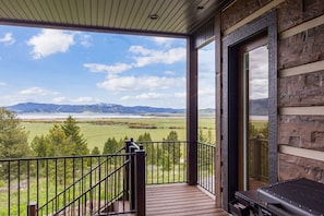 A balcony with a view of a lake and mountains, wooden railings, and a grill. - Trumpeter Swan,4Br/3 1/2Ba,BBQ,Firepit,Best views in island park,Lakeview,20m 2 YNP,Secluded,Deck (Island Park)