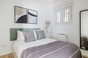 Cozy retreat with a neatly made bed, green headboard, and two framed artworks.