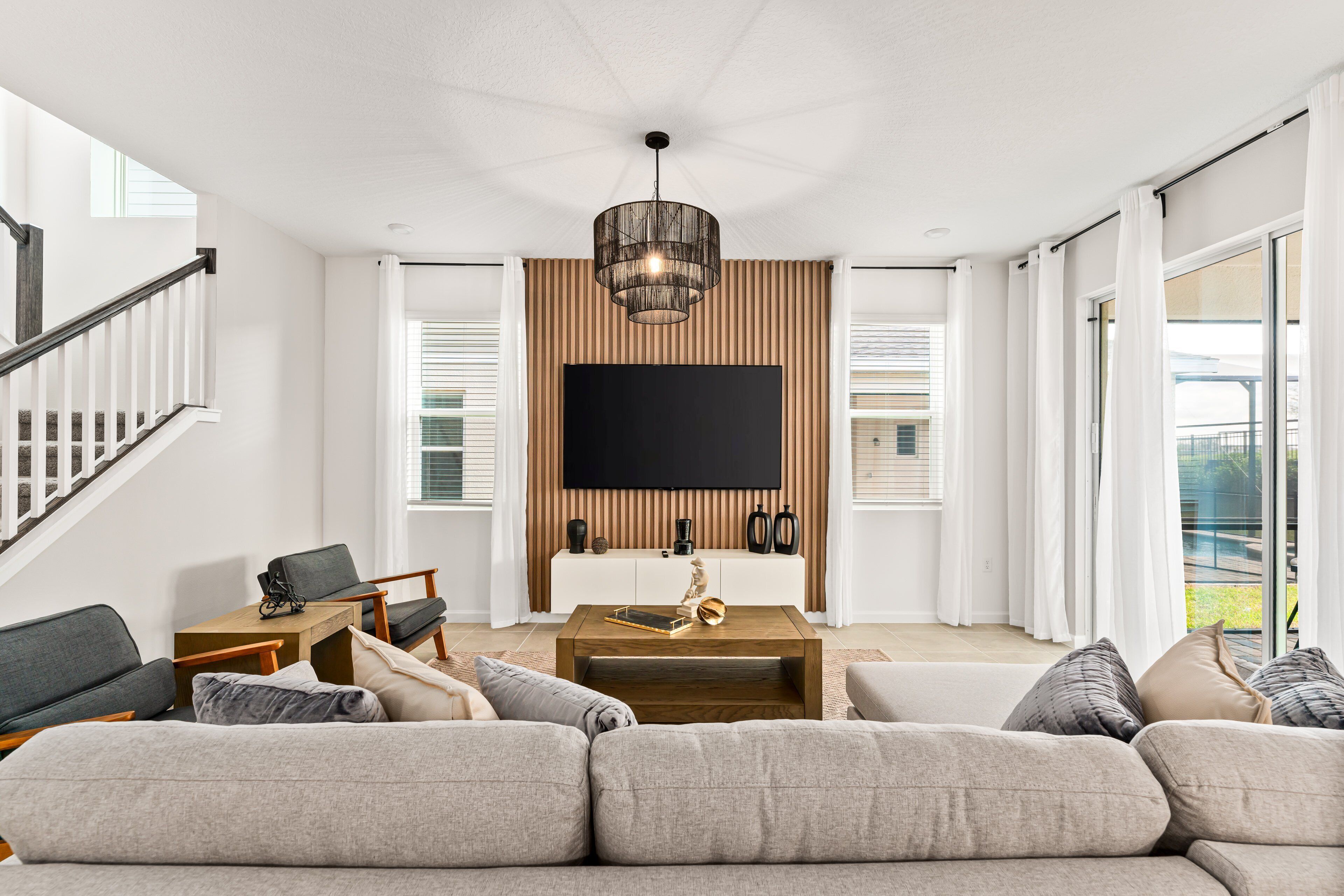 Un salon spacieux avec un grand canapé, une table basse et un téléviseur à écran plat fixé au mur.