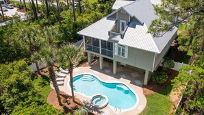A two-story house with a swimming pool, surrounded by trees and a well-maintained lawn.