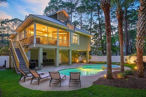 Una casa de dos pisos con un porche cubierto y una piscina.