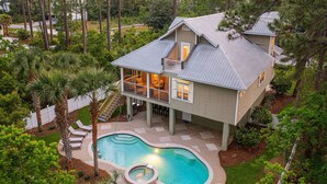 A two-story house with a large backyard, a swimming pool, and a covered patio area.