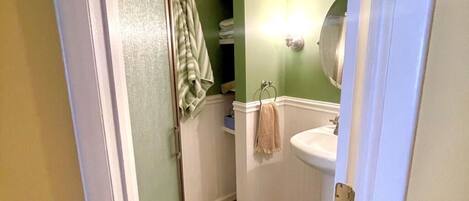 A bathroom with a white sink, green walls, and a beige floor.