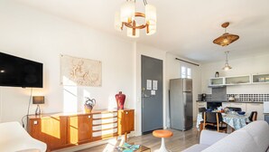 A modern living room with a sofa, a coffee table, a TV, and a dining area with a table and chairs. - Phichris by Interhome (Hyères)